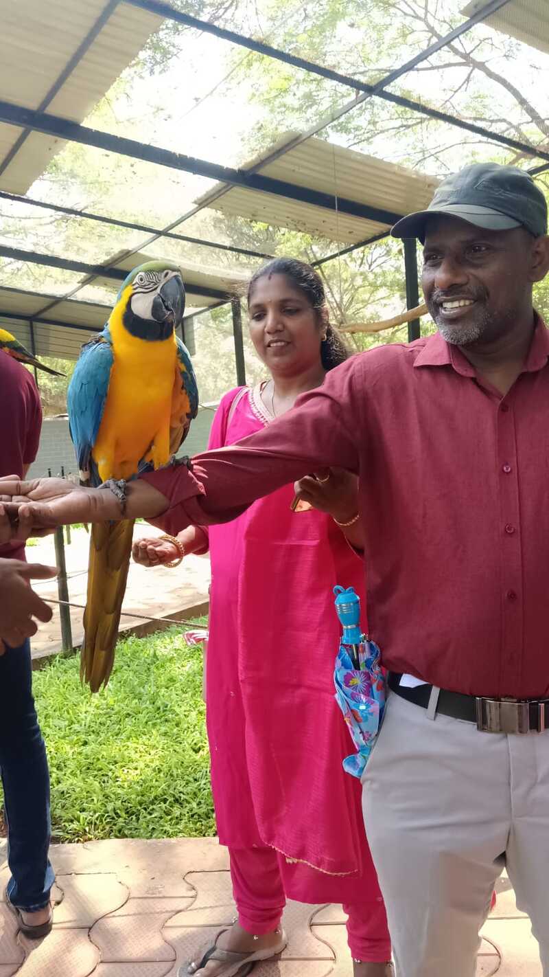 A participant from Thaaikarangal Charitable Trust smiles as a colorful blue-and-yellow macaw perches on his outstretched arm during the field trip. Guided by volunteers and fellow participants, the vision-disabled students experienced a meaningful connection with the birds through touch, sound, and close interaction, creating memorable sensory experiences. A participant from Thaaikarangal Charitable Trust smiles as a colorful blue-and-yellow macaw perches on his outstretched arm during the field trip. Guided by volunteers and fellow participants, the vision-disabled students experienced a meaningful connection with the birds through touch, sound, and close interaction, creating memorable sensory experiences.