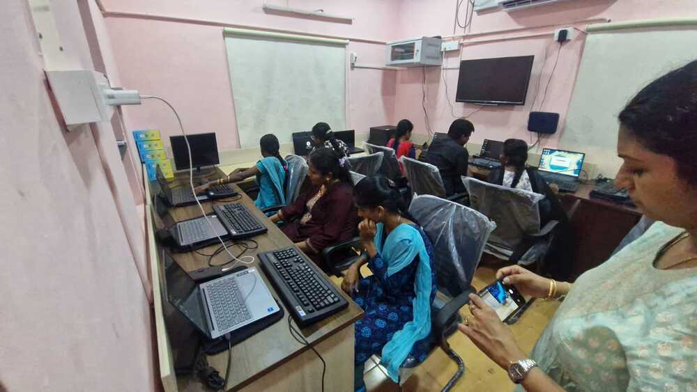Visually impaired female students use computers inside the newly inaugurated Digital Skill Center, while a staff member documents the activity.